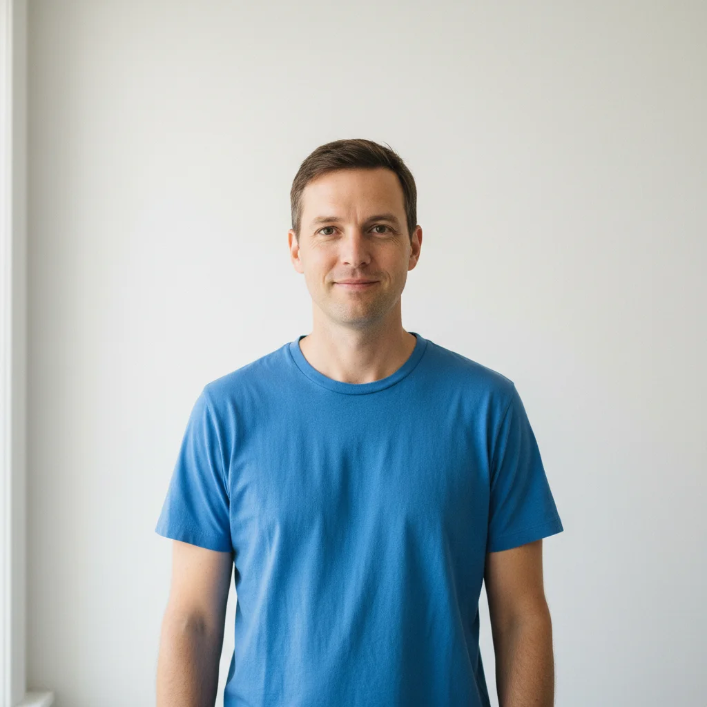 Casual portrait of a man in blue t-shirt against white wall