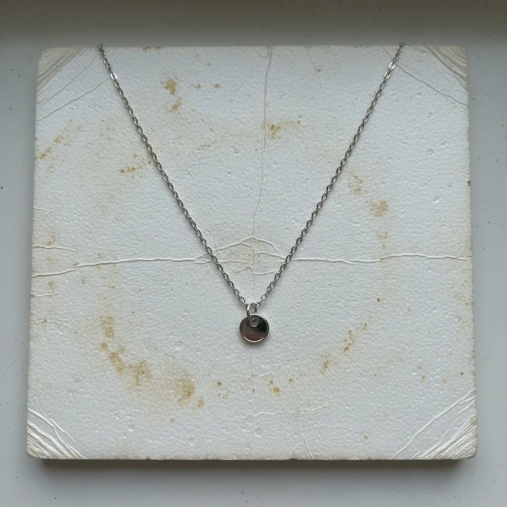 Silver necklace on yellowed dingy white background